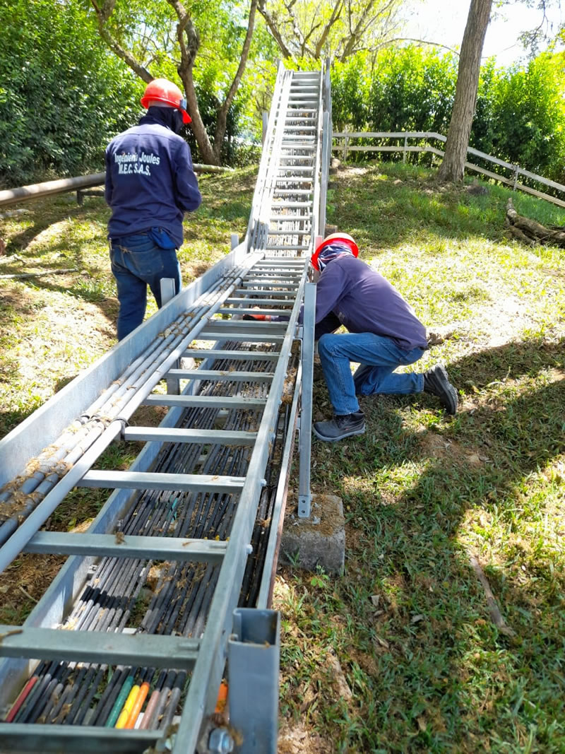 Dos técnicos de Ingeniería Joules instalando una bandeja portacables con cableado eléctrico